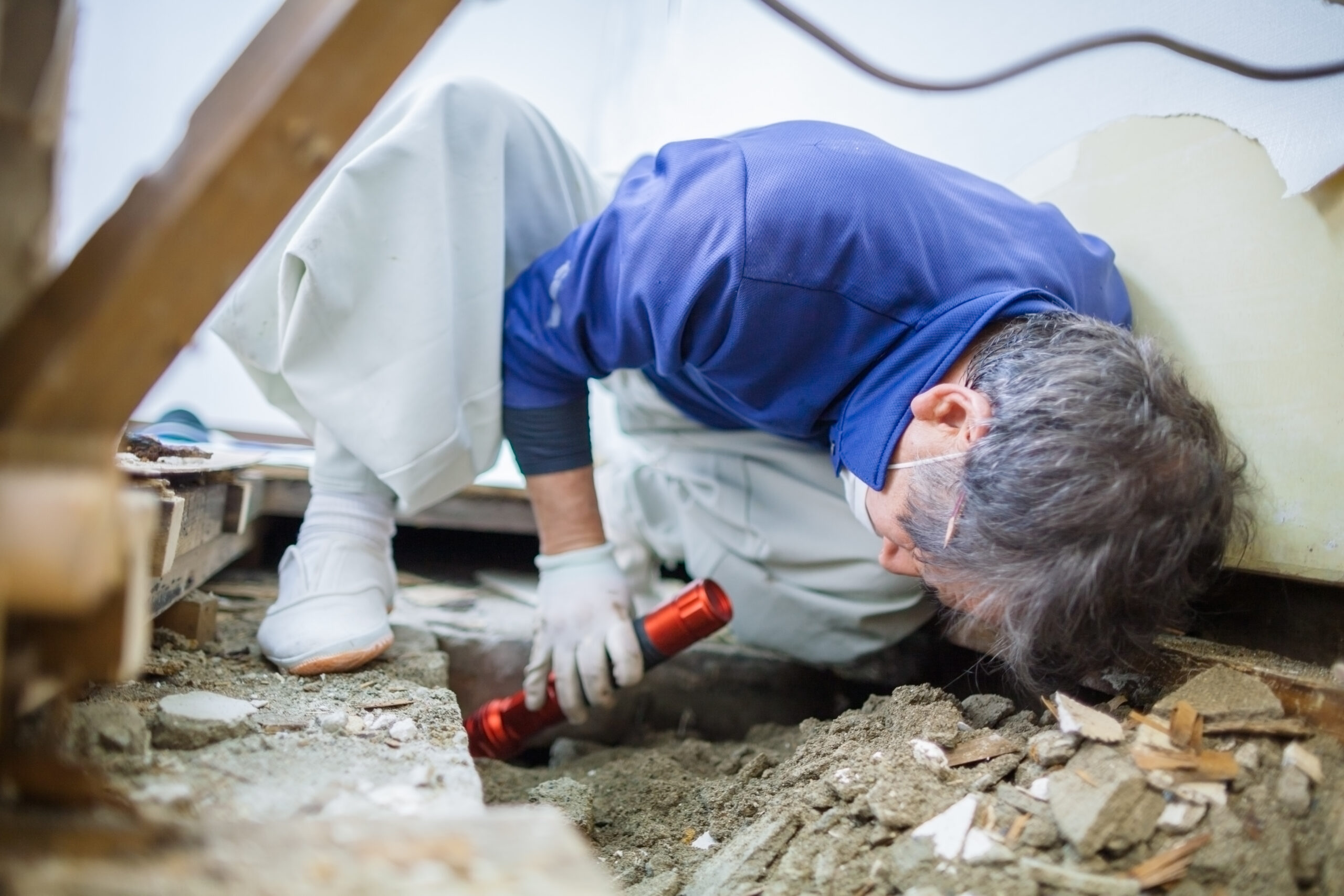 Worker examining space beneath floorboards