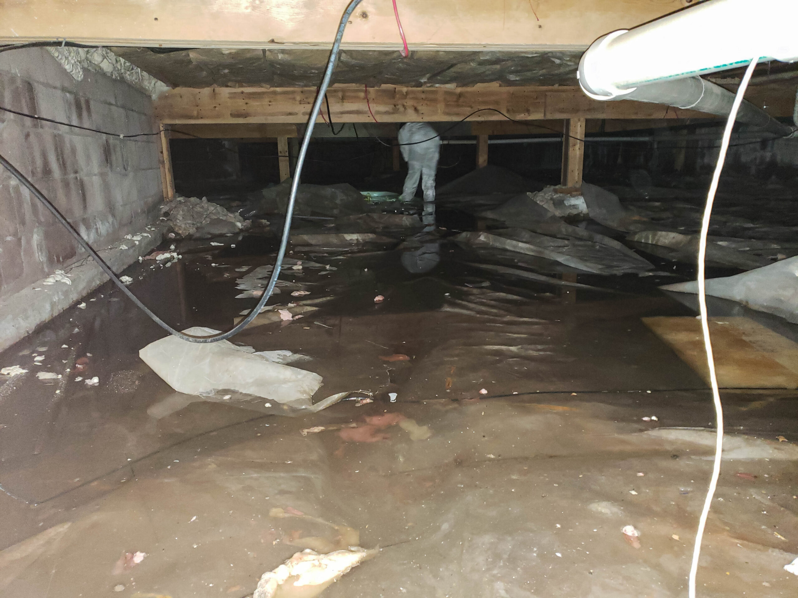 Flooded crawl space with worker in suit