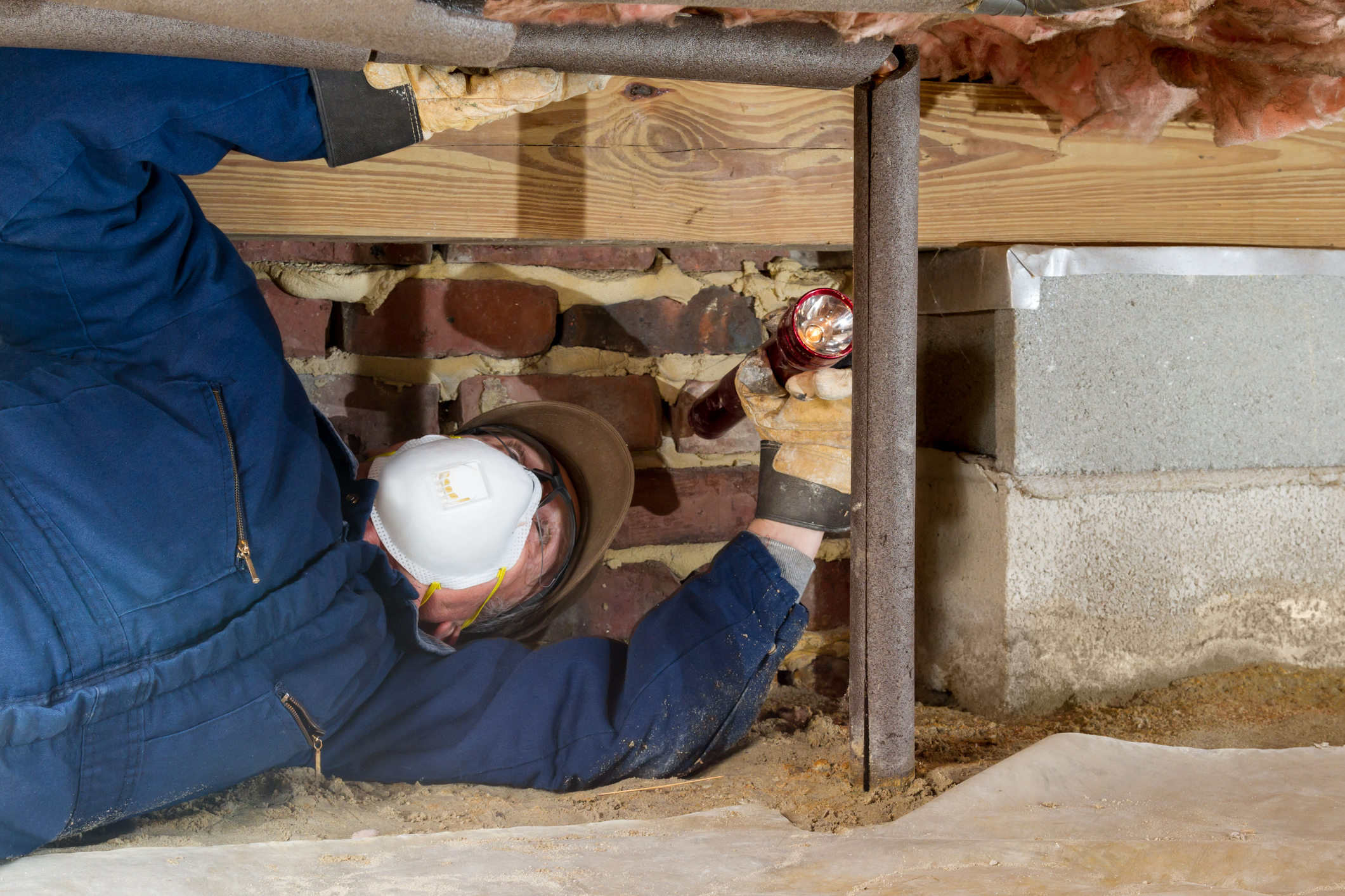 Man in crawl space with flashlight