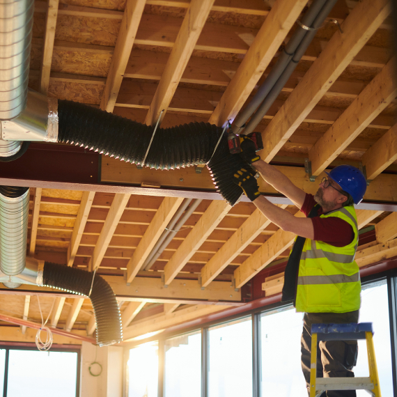 Worker on ladder fixing ventilation system