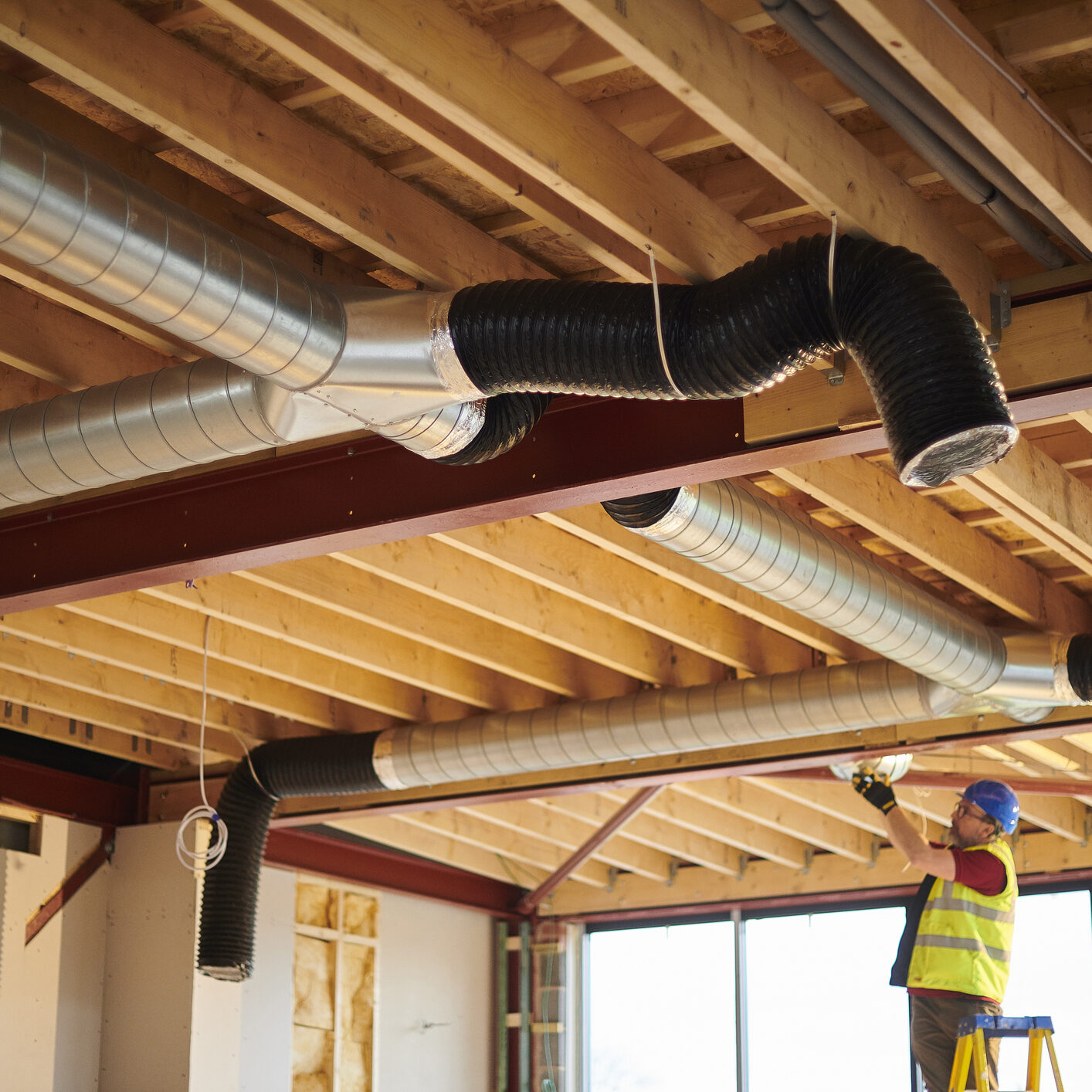 Man on ladder adjusting ductwork